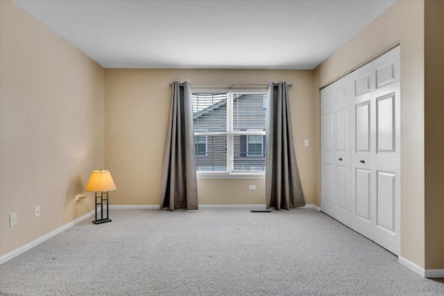 unfurnished bedroom with baseboards, carpet, and a closet