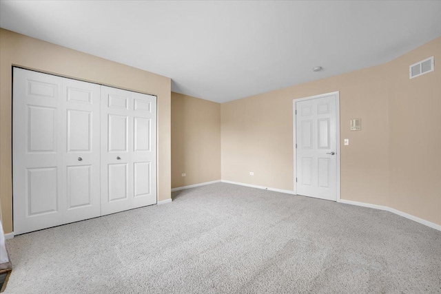 unfurnished bedroom featuring visible vents, carpet, baseboards, and a closet