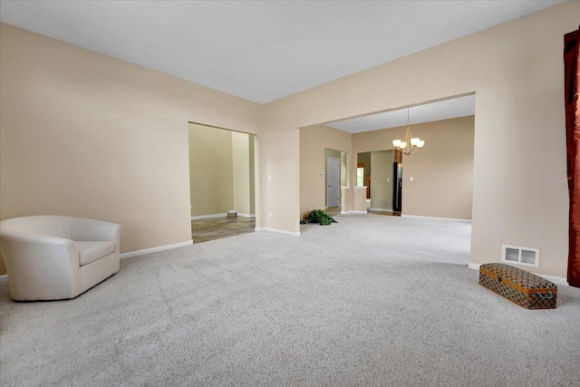 carpeted spare room with baseboards, visible vents, and a notable chandelier