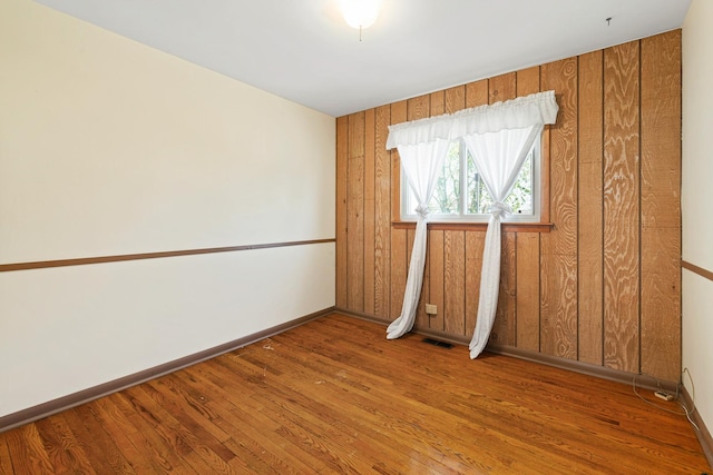 unfurnished room with visible vents, wood finished floors, and baseboards
