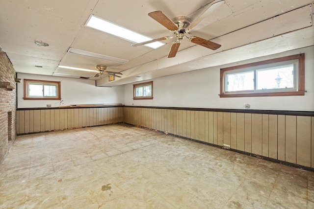 spare room featuring light floors, a wainscoted wall, and wood walls