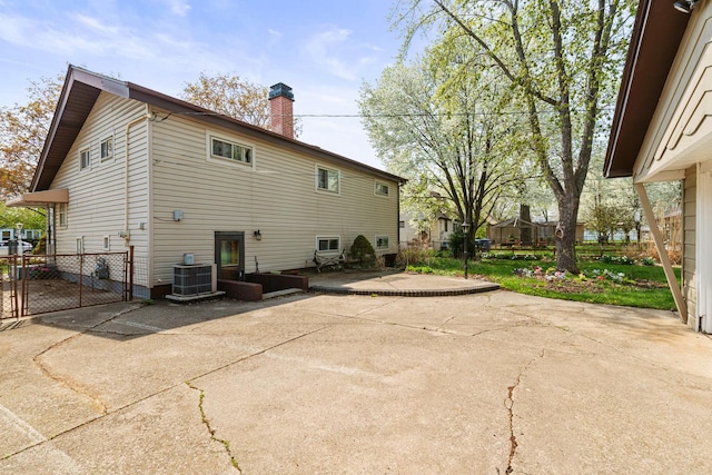 rear view of house with a patio, a chimney, a gate, fence, and central AC