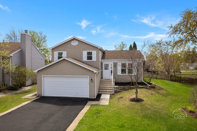 split level home with a front lawn, fence, a garage, and aphalt driveway