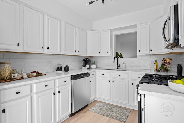 kitchen featuring white cabinetry, light wood-type flooring, appliances with stainless steel finishes, and a sink