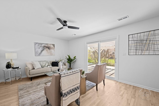 living room featuring visible vents, a ceiling fan, light wood finished floors, and baseboards
