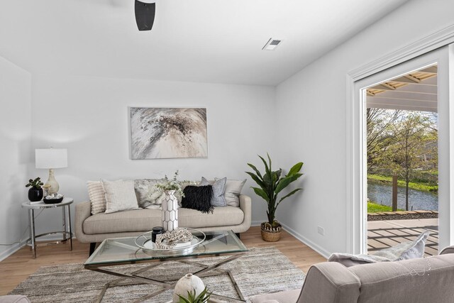 living room featuring baseboards, visible vents, wood finished floors, and a water view