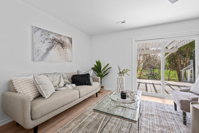 living room featuring wood finished floors, visible vents, and baseboards