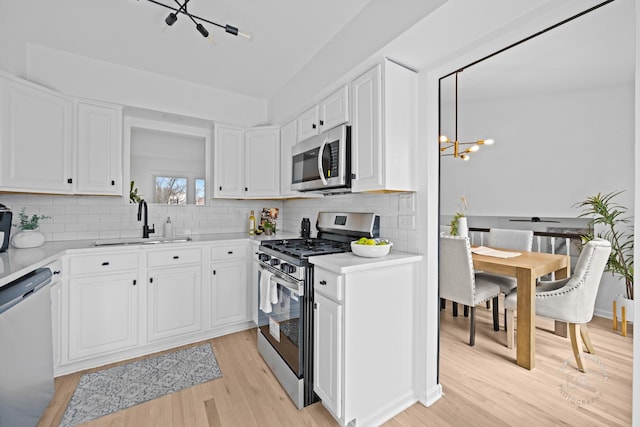 kitchen with stainless steel appliances, light countertops, light wood finished floors, and a sink