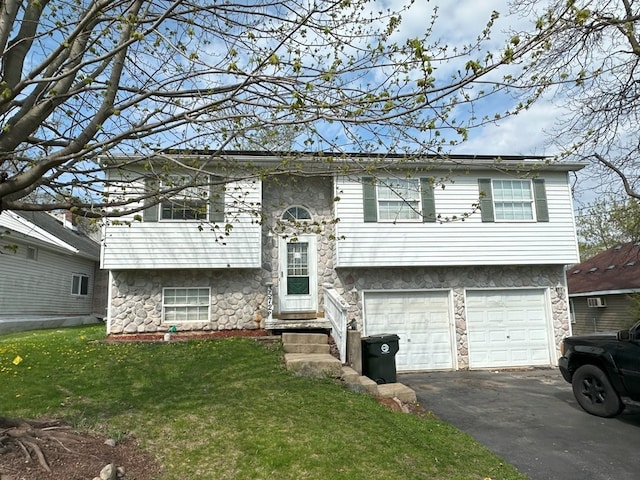 bi-level home featuring a front lawn, aphalt driveway, an attached garage, and stone siding