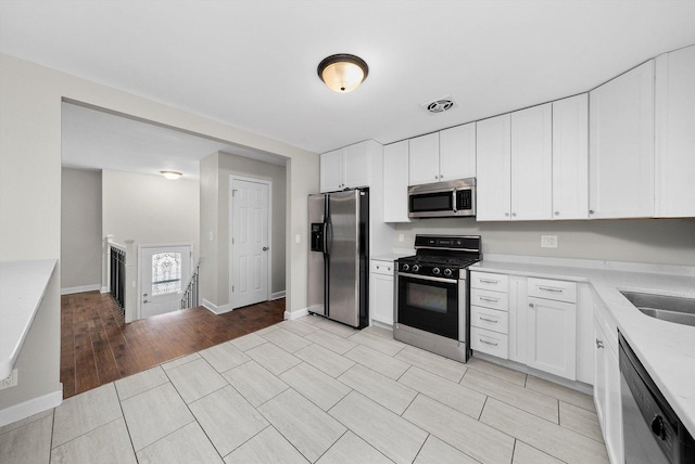 511 Freeman Ave, Streamwood, IL 60107 - kitchen with white cabinetry, light countertops, stainless steel appliances, and baseboards