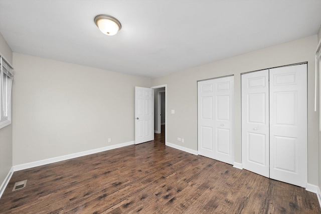 511 Freeman Ave, Streamwood, IL 60107 - unfurnished bedroom featuring two closets, baseboards, visible vents, and dark wood finished floors