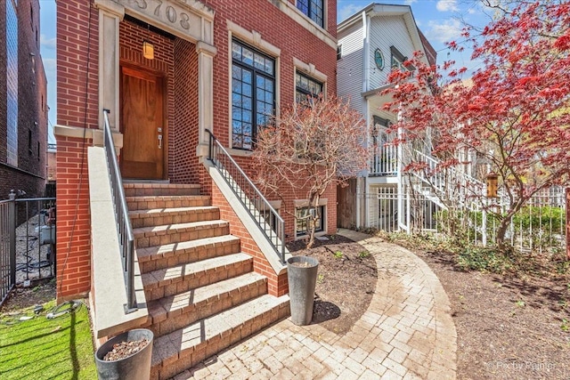 property entrance with brick siding and fence