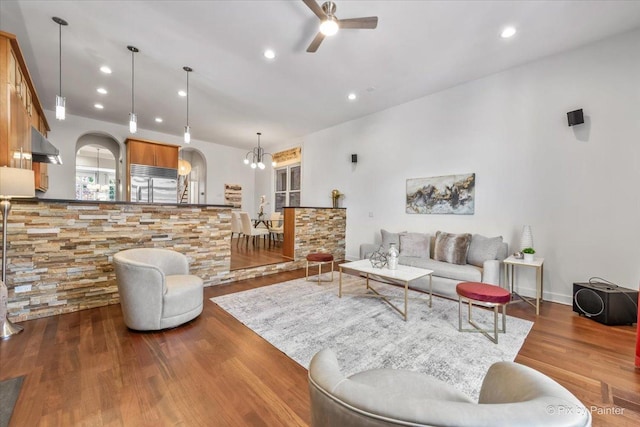 living area featuring arched walkways, ceiling fan, recessed lighting, and wood finished floors