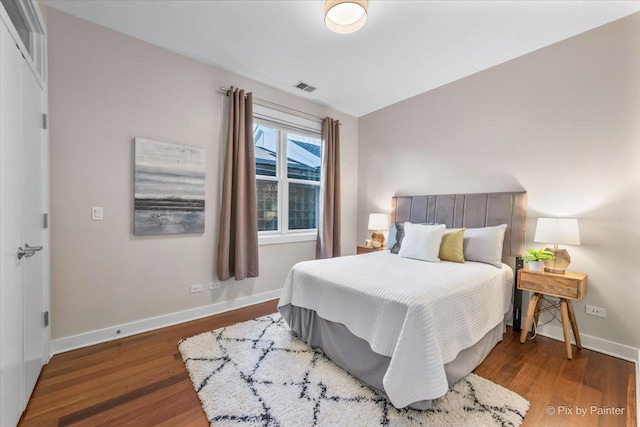 bedroom featuring visible vents, baseboards, and wood finished floors