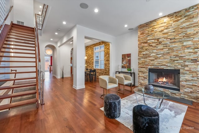 living room featuring visible vents, stairs, wood finished floors, a fireplace, and arched walkways