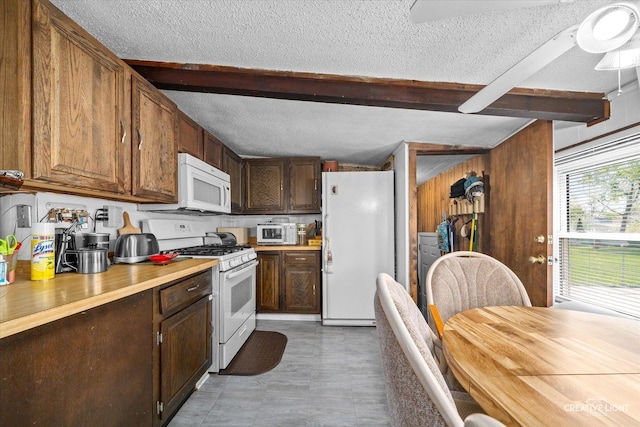 kitchen with white appliances, beamed ceiling, a ceiling fan, a textured ceiling, and light countertops