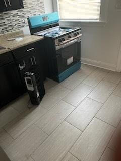 kitchen with gas stove, tasteful backsplash, light countertops, and dark cabinetry