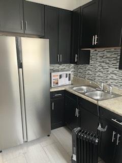 kitchen featuring a sink, dark cabinetry, and radiator