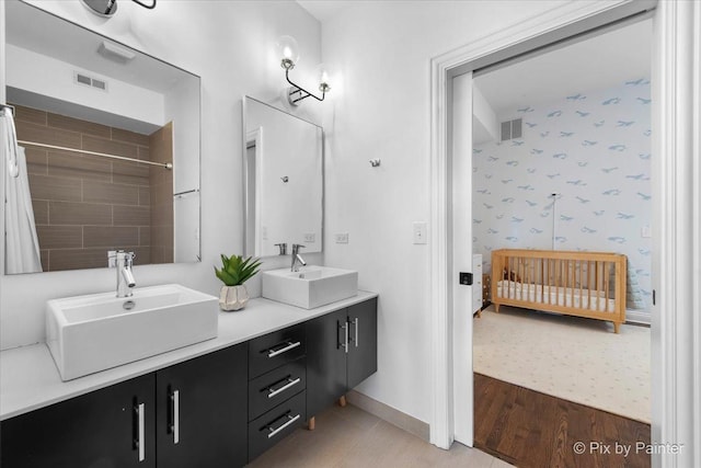 full bath featuring visible vents, a sink, and wallpapered walls