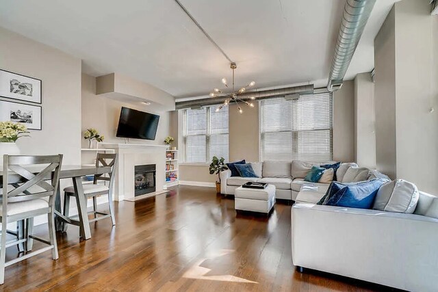 living room with baseboards, a chandelier, dark wood-style floors, and a fireplace