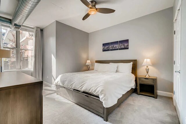 bedroom featuring light colored carpet, a ceiling fan, and baseboards