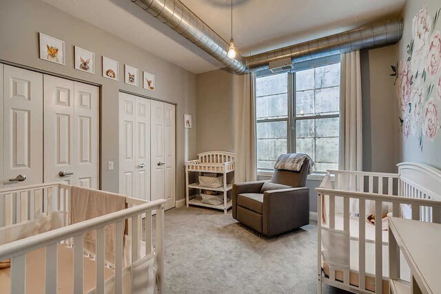 bedroom featuring multiple closets, visible vents, and light colored carpet