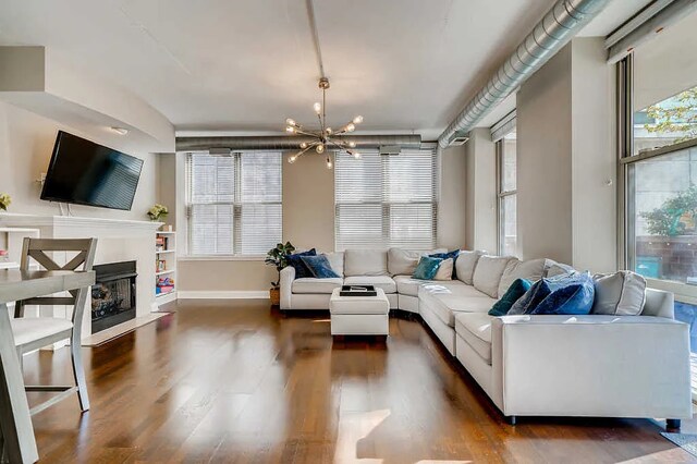 living room featuring dark wood-type flooring, baseboards, a chandelier, and a fireplace