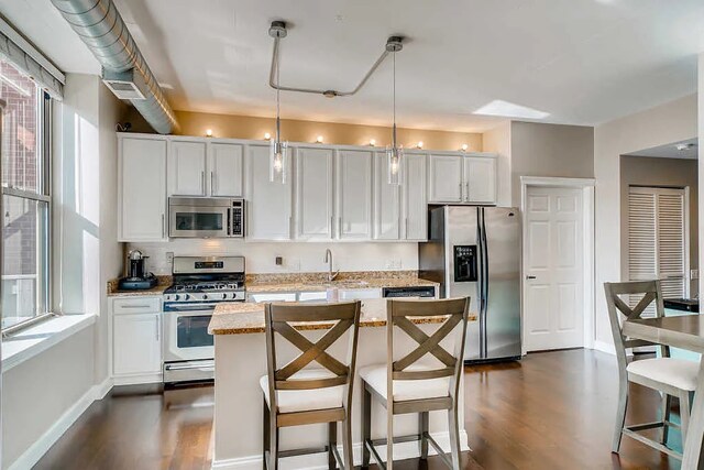 kitchen featuring a kitchen island, dark wood-style floors, a wealth of natural light, and stainless steel appliances