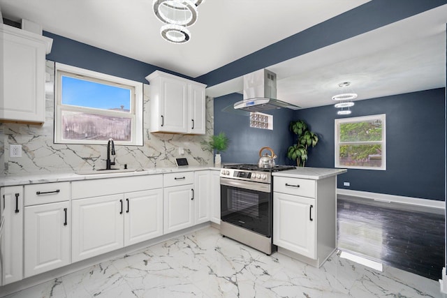 kitchen with exhaust hood, a sink, stainless steel gas range oven, a chandelier, and backsplash