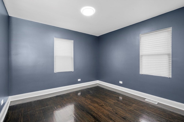 unfurnished room with baseboards, dark wood finished floors, and visible vents