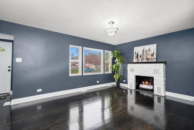 unfurnished living room featuring baseboards, wood finished floors, and a fireplace