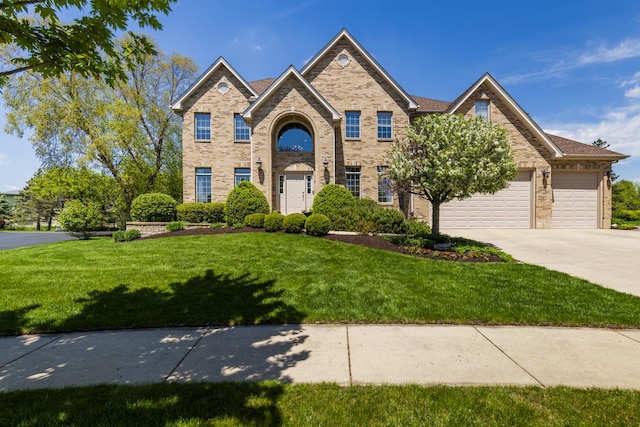 view of front of house featuring driveway, a front yard, brick siding, and a garage