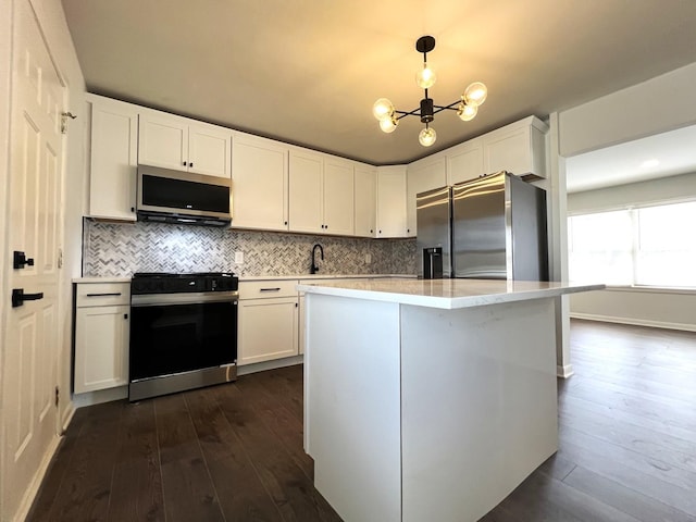 kitchen with appliances with stainless steel finishes, dark wood-style floors, light countertops, and white cabinets