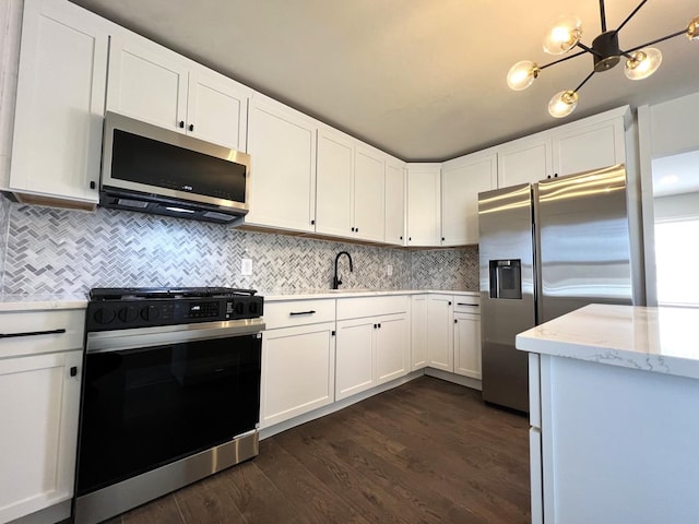 kitchen featuring stainless steel appliances, white cabinets, dark wood-style floors, and tasteful backsplash