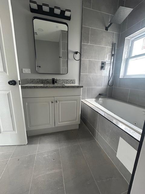 bathroom with tiled shower / bath combo, vanity, and tile patterned flooring