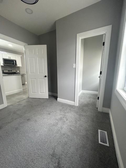 unfurnished bedroom with baseboards, visible vents, and light carpet