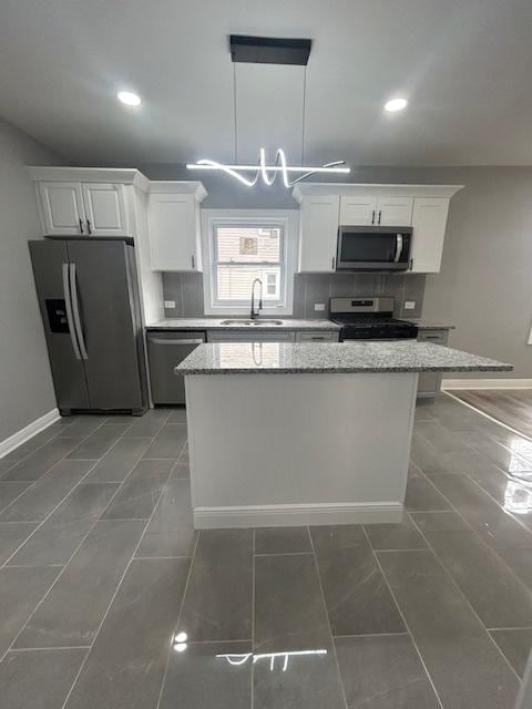 kitchen featuring white cabinetry, stainless steel appliances, baseboards, and a sink