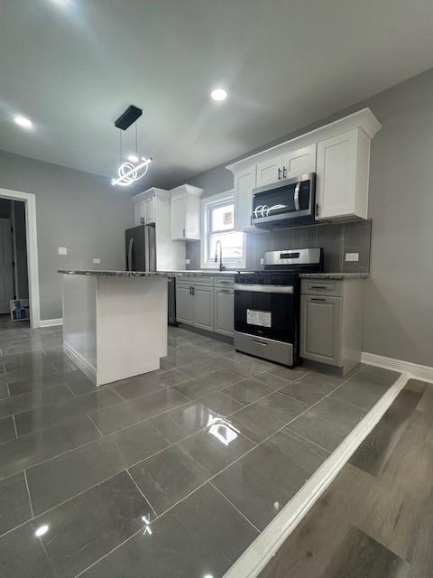 kitchen featuring baseboards, appliances with stainless steel finishes, and white cabinetry