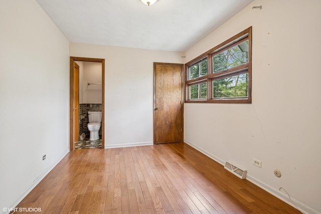 23460W N Lakewood Ln, Lake Zurich, IL 60047 - unfurnished bedroom with ensuite bath, light wood-type flooring, visible vents, and baseboards