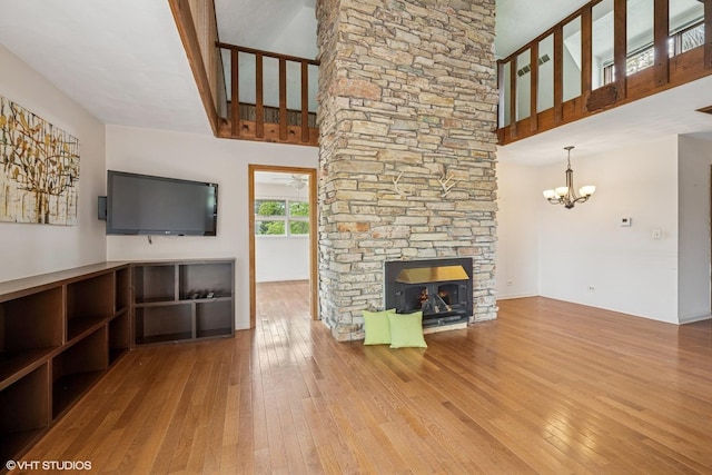 23460W N Lakewood Ln, Lake Zurich, IL 60047 - unfurnished living room with a stone fireplace, hardwood / wood-style floors, an inviting chandelier, and a towering ceiling