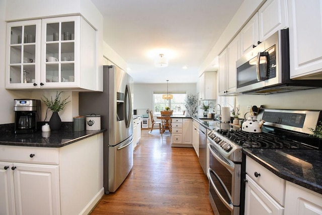 kitchen featuring white cabinets, stainless steel appliances, glass insert cabinets, and wood finished floors