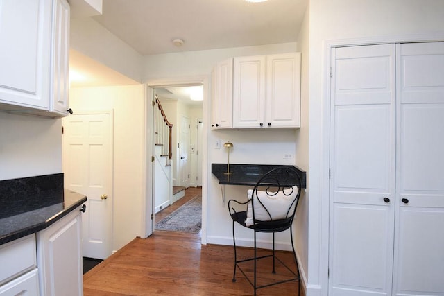 kitchen with dark stone counters, white cabinetry, and dark wood-type flooring