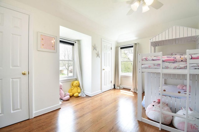bedroom featuring baseboards, multiple windows, and wood finished floors