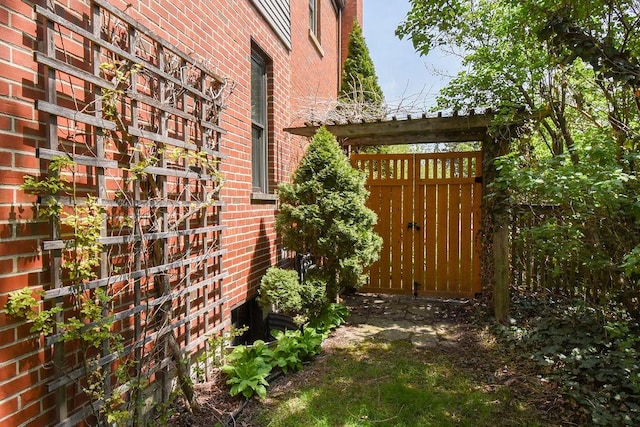 view of side of property featuring brick siding and a gate