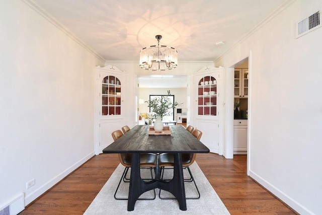 dining space with visible vents, ornamental molding, dark wood-type flooring, and a chandelier