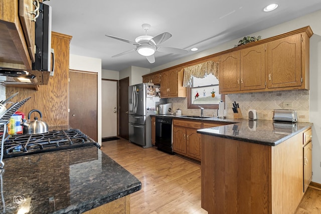kitchen with a sink, ceiling fan, light wood finished floors, black dishwasher, and stainless steel refrigerator with ice dispenser