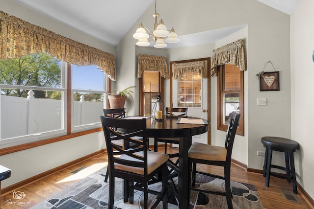 dining area with wood finished floors, vaulted ceiling, baseboards, visible vents, and a notable chandelier