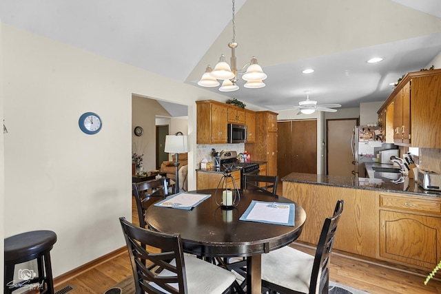 dining area featuring recessed lighting, light wood-style flooring, vaulted ceiling, ceiling fan with notable chandelier, and baseboards