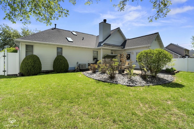 rear view of house featuring a chimney, fence, central air condition unit, a patio area, and a lawn