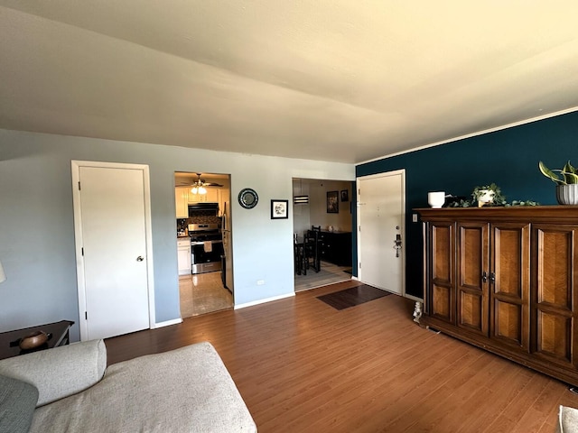 living area with wood finished floors, baseboards, and a ceiling fan